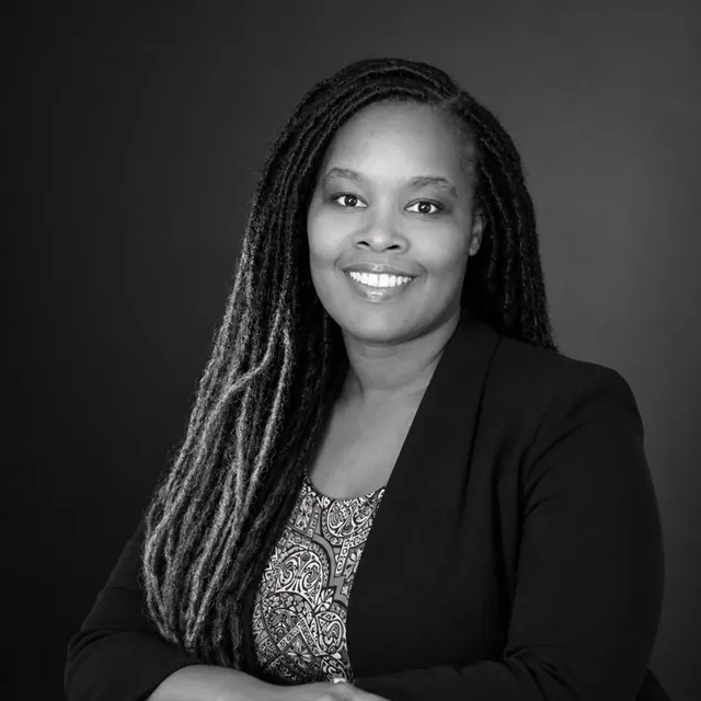 Black and white portrait of Kim Herbert, founder of Solopreneur At Work, smiling in a black blazer